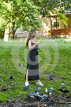 Beautiful girl feeds bread to pigeons in a city Park in the summer