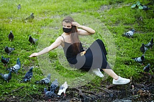 Beautiful girl feeds bread to pigeons in a city Park in the summer