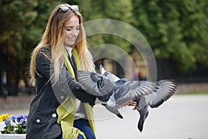 Beautiful girl feeds city pigeons with hands