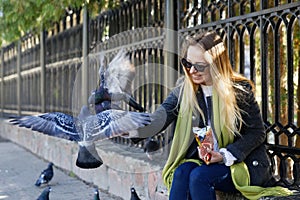 Beautiful girl feeds city pigeons with hands