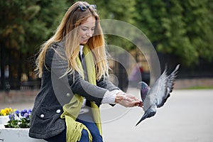 Beautiful girl feeds city pigeons with hands