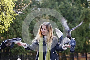 Beautiful girl feeds city pigeons with hands