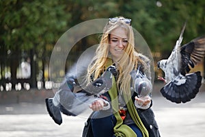 Beautiful girl feeds city pigeons with hands