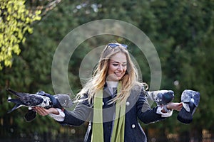 Beautiful girl feeds city pigeons with hands