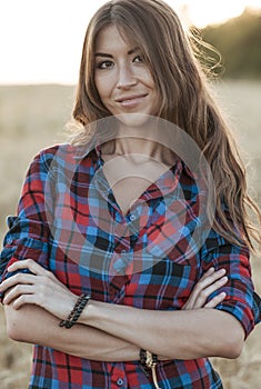 Beautiful girl field. Summer in nature. Happy smiling looking in frame. In the evening shirt a brunette woman, a close