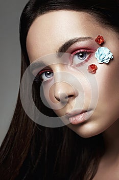 Beautiful Girl with Flowers on face. colorful make-up