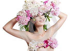 Beautiful girl with flowers peonies. Portrait of a young woman with flowers in her hair and a dress of flowers.