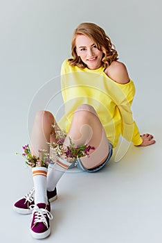 beautiful girl with flowers in socks sitting and smiling at camera