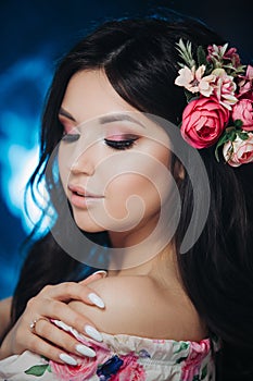 Beautiful girl with flowers. Spring woman. Lady with bright makeup and a flowering branch in her hair. Spring time. On dark