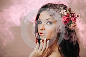 Beautiful girl with flowers. Spring woman. Lady with bright makeup and a flowering branch in her hair. Spring time. On a pink