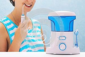 Beautiful girl flushes her teeth with an oral irrigator. the woman smiles and holds the irrigator handle. cleaning of teeth at hom