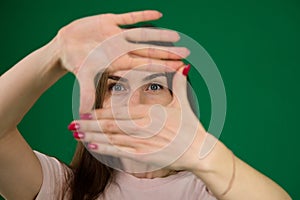 beautiful girl framing her face with her hands different emotions of a young girl on a green background chromakey