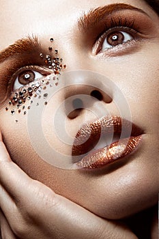 Beautiful girl with a gentle make-up and crystals on the face. Close-up portrait.