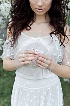 Beautiful girl with gentle make-up long light dress among the flowering trees walks in the spring garden on a warm sun