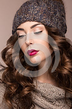 Beautiful girl with gentle makeup, curls in brown knit hat. Warm winter image. Beauty face.