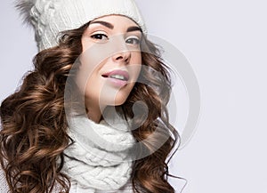 Beautiful girl with gentle makeup, curls and smile in white knit hat. Warm winter image. Beauty face.