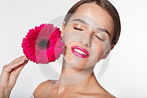 Beautiful girl with gerbera flower near face