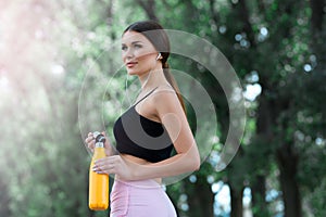Beautiful girl getting ready for jogging in the park. With thermos bottle in hand.