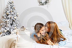 Beautiful girl giving a present to her little brother at the christmas tree