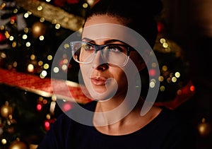 Beautiful girl with glasses in front of christmas tree