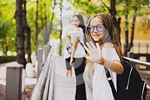 The beautiful girl with glasses looks goodbye to the cameras, heading to school.