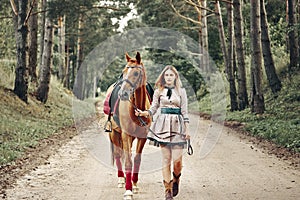 Beautiful girl goes on the road with a horse