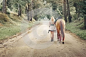 Beautiful girl goes on the road with a horse