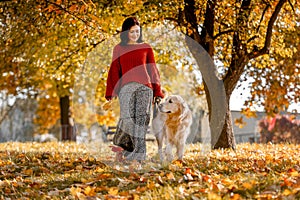 Beautiful girl with golden retriever dog in autumn park