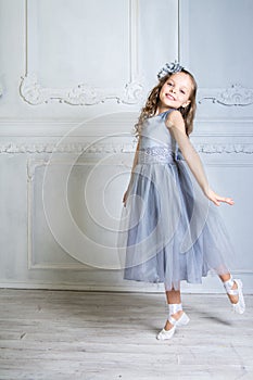 Beautiful girl in gray dress and pointe shoes is posing in the r