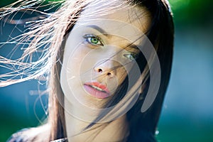 Beautiful girl with green eyes in city park. Woman beauty face portrait