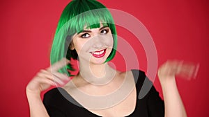 Beautiful girl in a green wig grimaces, fools around and expresses different emotions. Video