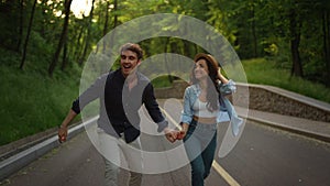 Beautiful girl and guy jumping in park. Young couple having fun outside