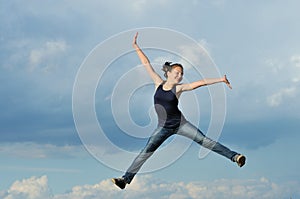 Beautiful girl in gymnastic jump against blue sky