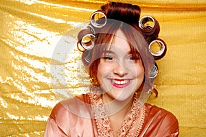 Beautiful girl in hair curlers isolated on gold