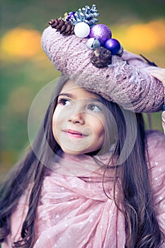 Beautiful girl with a hand-made pinkish Christmas wreath used as a hat