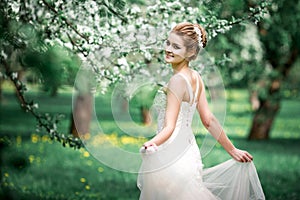 Beautiful girl hands with a branch of a blossoming apple tree. Young beautiful blonde woman in blooming garden.