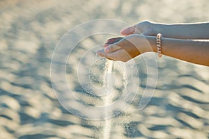 Beautiful girl hands scatter the sand on the beach. Concept - time is running out, nothing lasts forever. Copy space for text