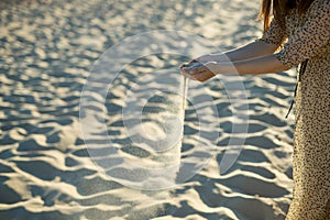 Beautiful girl hands scatter the sand on the beach. Concept - time is running out, nothing lasts forever. Copy space for text