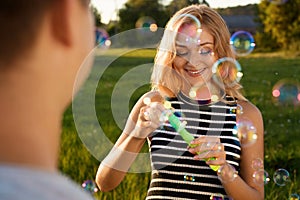 A beautiful girl with a happy smile blowing soap bubbles on the