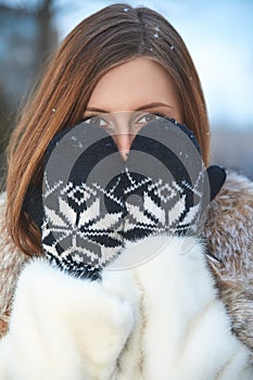 Beautiful girl has closed the face by a mitten. Winter outdoor
