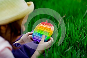 A beautiful girl in a hat, playing with a toy to drink on the green grass.in the park, on a summer day