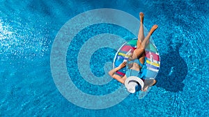 Beautiful girl in hat in swimming pool aerial drone view from above, woman relaxes and swims on inflatable ring donut and has fun