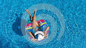 Beautiful girl in hat in swimming pool aerial drone view from above, woman relaxes and swims on inflatable ring donut and has fun