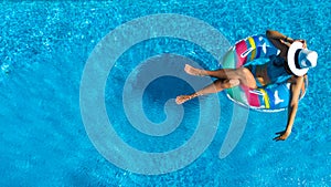 Beautiful girl in hat in swimming pool aerial drone view from above, woman relaxes and swims on inflatable ring donut and has fun