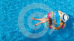 Beautiful girl in hat in swimming pool aerial top view from above, woman relaxes and swims on inflatable ring donut and has fun