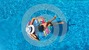 Beautiful girl in hat in swimming pool aerial top view from above, woman relaxes and swims on inflatable ring donut and has fun