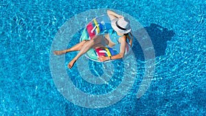 Beautiful girl in hat in swimming pool aerial top view from above, woman relaxes and swims on inflatable ring donut and has fun