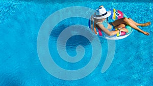 Beautiful girl in hat in swimming pool aerial top view from above, woman relaxes and swims on inflatable ring donut and has fun photo