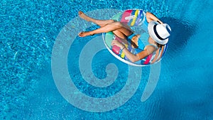 Beautiful girl in hat in swimming pool aerial top view from above, woman relaxes and swims on inflatable ring donut and has fun photo