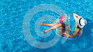 Beautiful girl in hat in swimming pool aerial top view from above, young woman relaxes and swims on inflatable ring donut photo